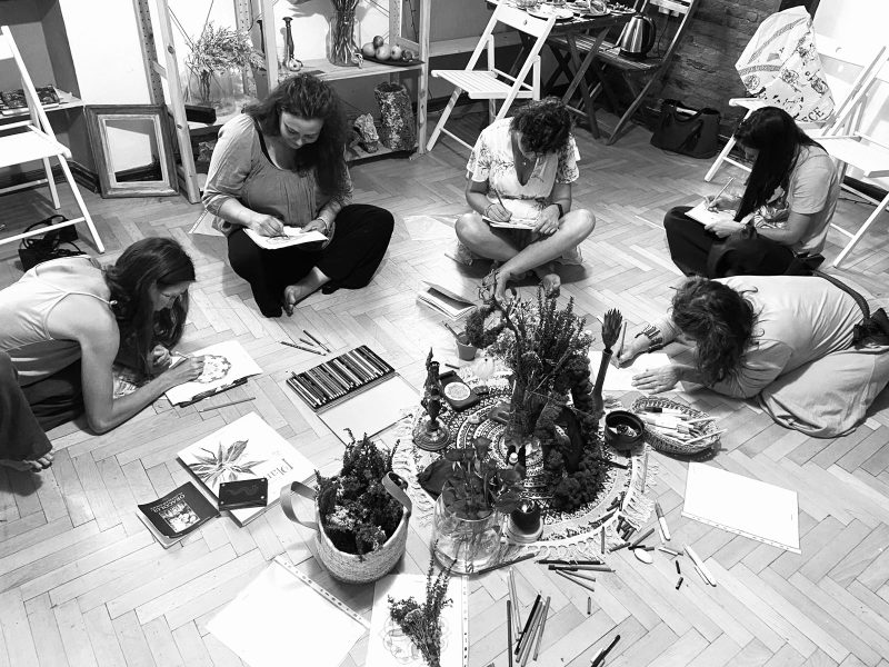 Women seated in a circle around plants