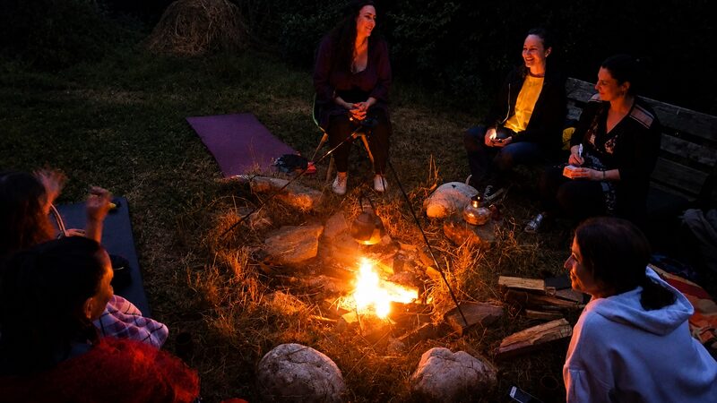 Participants seated in a circle around a fire